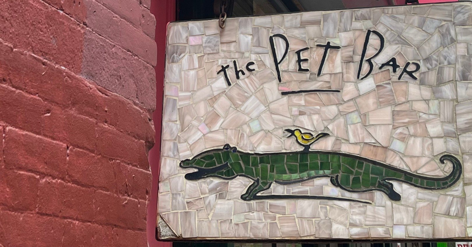 こちらをみて笑うワニと背中に乗った黄色い鳥が可愛いNYのSOHOにあるペットバーのモザイク看板